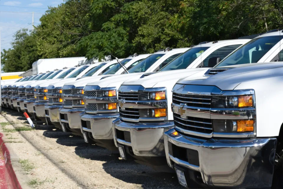 A row of white pickup trucks at a car dealership.